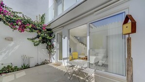 A modern house with a glass door leading to a staircase, a dining area with a table and chairs, and a birdhouse on the wall. - Charming architect-designed house in the heart of Tavira (Tavira)