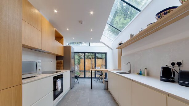A modern kitchen with a skylight, built-in appliances, and a view of the outdoors. - Bright Beautiful Modern 2 Bed Home Pass The Keys (Cambridge)