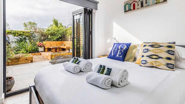 Un dormitorio con una cama grande, vistas a un jardín y un cuadro en la pared.