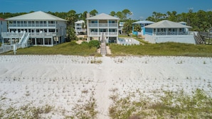 A beachfront property with multiple buildings, including a large house with a balcony and a smaller structure with a deck. - Gulf-front, private pool, pets welcome! (Port Saint Joe)