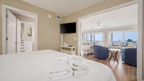 A hotel room with a large bed, a TV, a balcony with seating, and a view of the city. - Gulf-front, private pool, pets welcome! (Port Saint Joe)