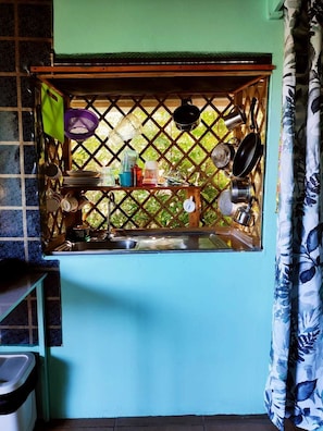 Kitchen with sink, countertop, and drying rack, offering a view of the outdoors through a window with a lattice design.