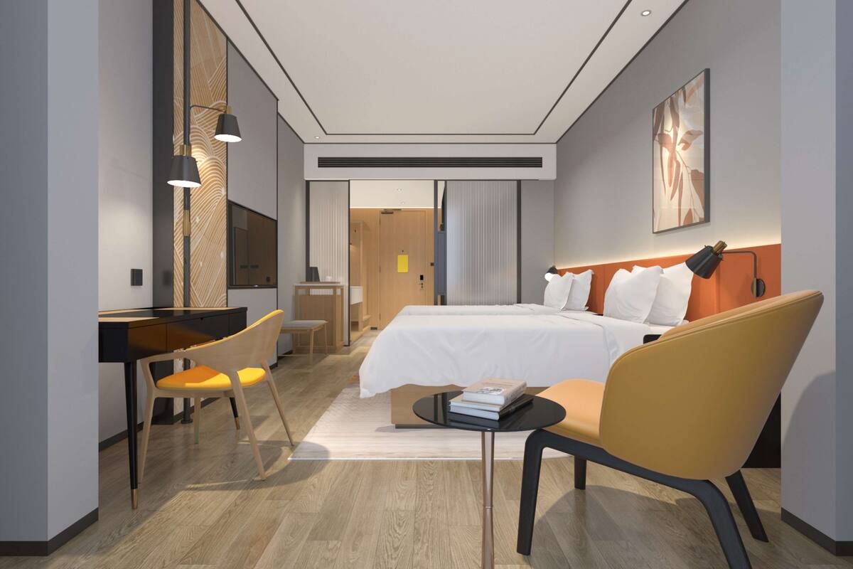 Ein modernes Hotelzimmer mit einem großen Bett, einem Schreibtisch und einem Stuhl. Eine Tür führt in einen weiteren Raum.