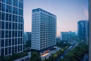 Un hôtel moderne de grande hauteur, doté d’une façade en verre, entouré d’autres immeubles et d’arbres.