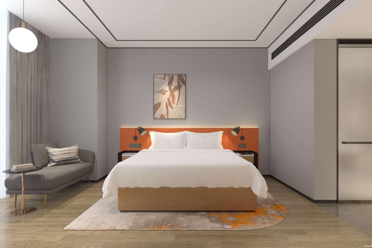Ein modernes Schlafzimmer mit einem großen Bett, einer Couch und einem kleinen Tisch.