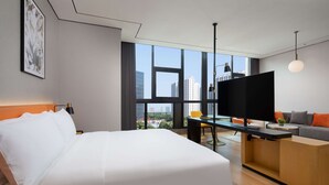 A modern hotel room with a large bed, a desk with a computer, a sofa, and a TV. - Hilton Garden Inn Hangzhou Xiaoshan (Hangzhou)