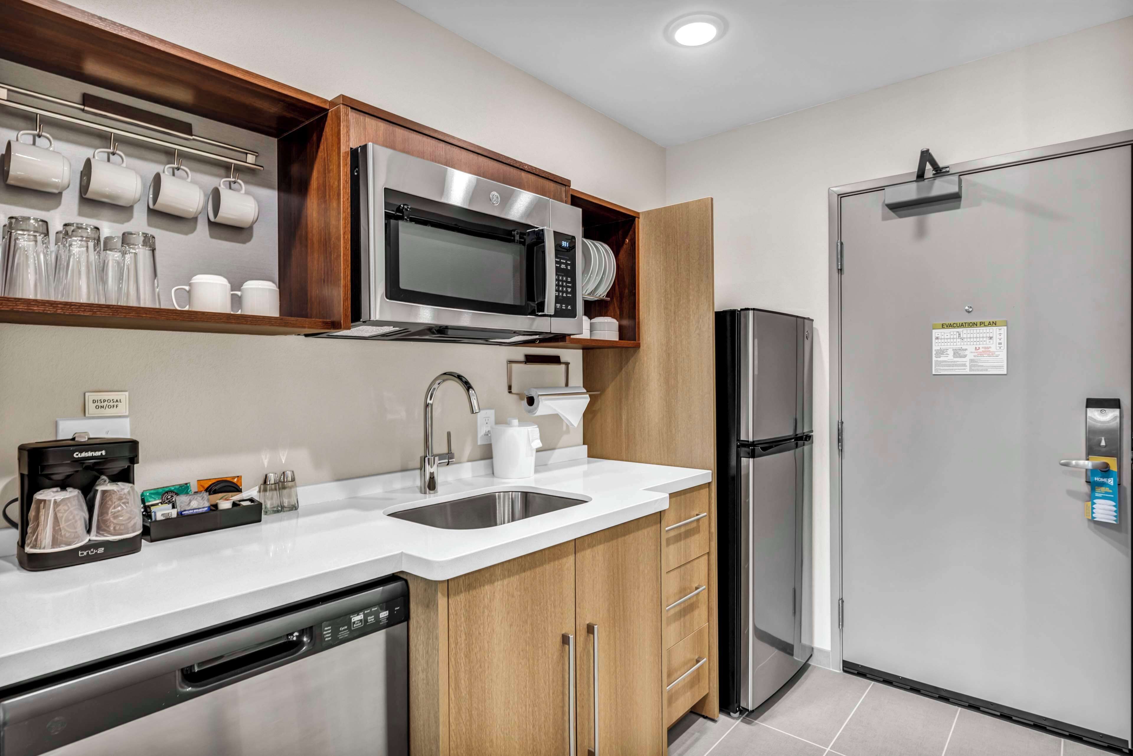 A modern kitchen with a built-in microwave, stainless steel refrigerator, and a sink.