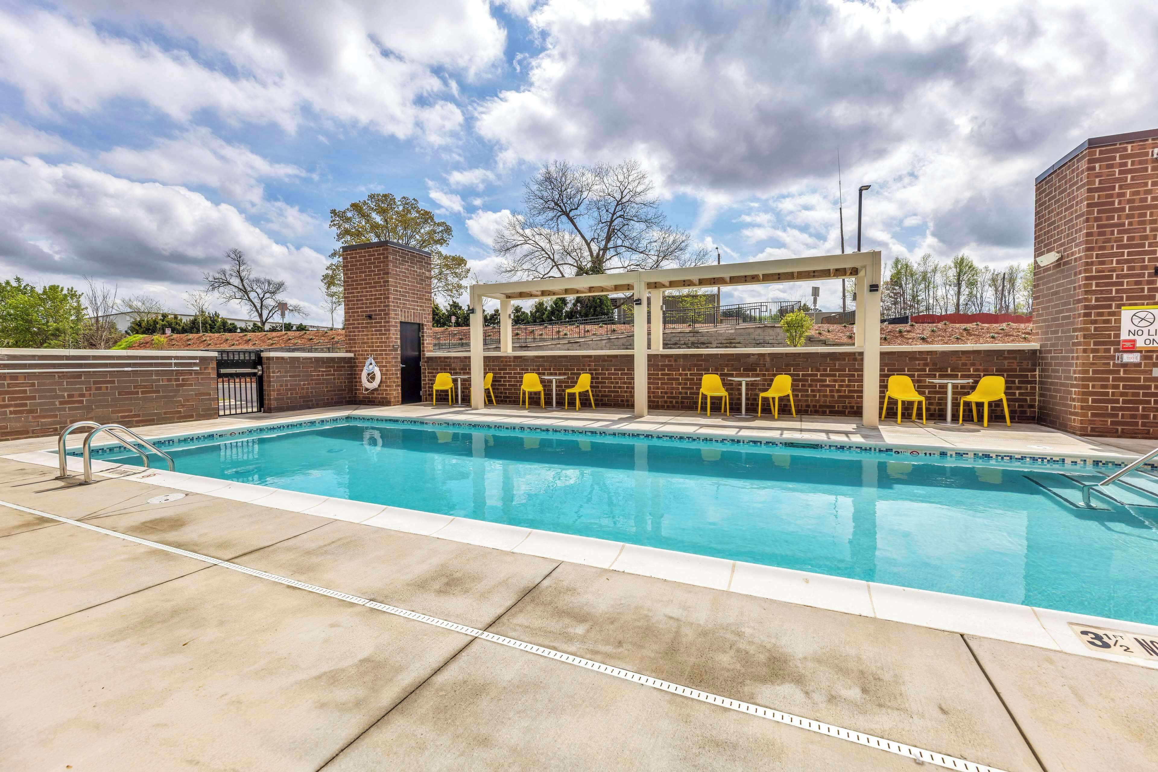 Une piscine avec des chaises jaunes et un espace de repos abrité.
