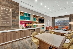 A modern hotel lobby with a coffee bar, seating area, and a large window offering a view.