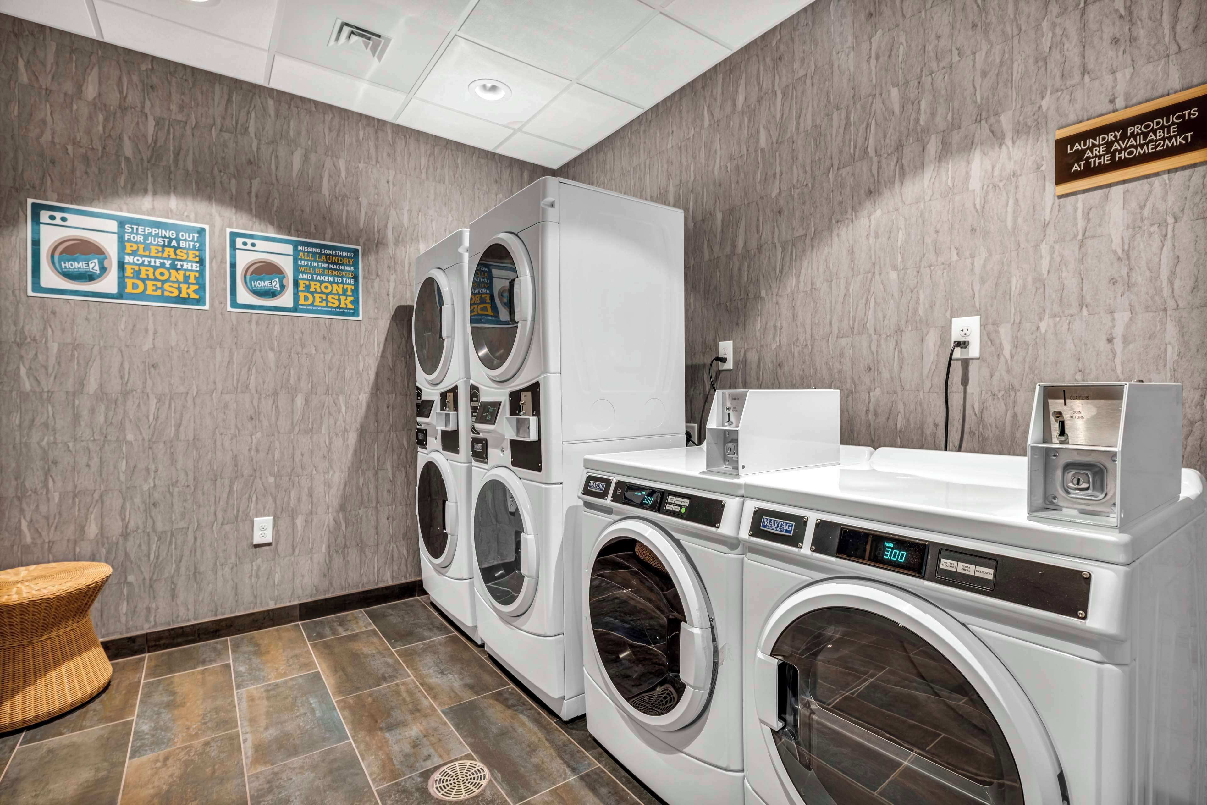 A laundry room with multiple washing machines, a sink, and a wicker chair.