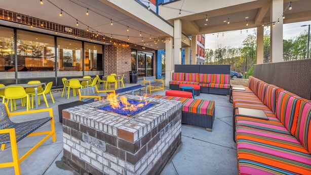 An outdoor patio with a fire pit, yellow chairs, and colorful seating.