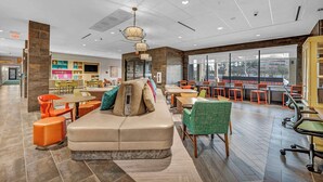 A modern lounge area with a sofa, chairs, and a dining area with tables and chairs.