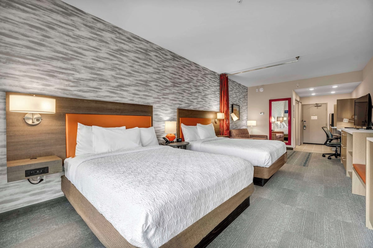 Een hotelkamer met twee bedden, een bureau en een televisie.