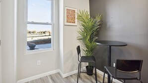 Una habitación con un ventanal grande, una planta en maceta y una pequeña mesa redonda con dos sillas.