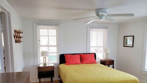 A bedroom with a bed, two bedside tables, a ceiling fan, and a window with blinds. - Miss Niccies - 2BR home close to town, Lg Screened porch. NO LINENS PROVIDED (Chincoteague)