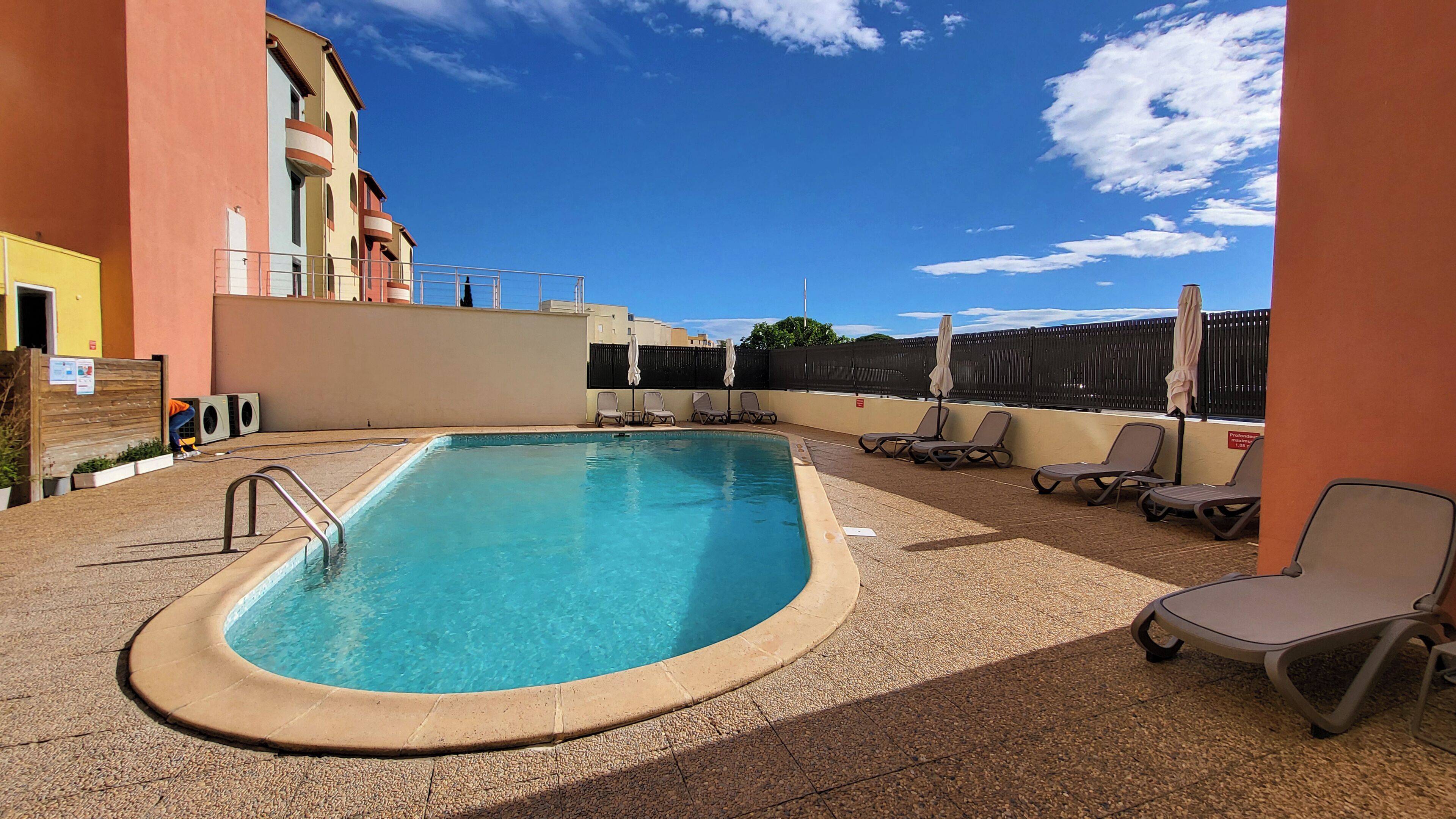 Piscina com espreguiçadeiras e área de estar coberta.