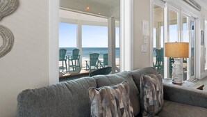 A living room with a view of the beach, a sofa, chairs, and a lamp. - Beach House - Sweet n Salty by PHG (Panama City Beach)