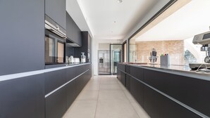 Una cocina moderna con muebles oscuros, una isla central y vistas a la ciudad.