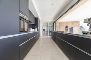 A modern kitchen with dark cabinetry, a central island, and a view of the city.