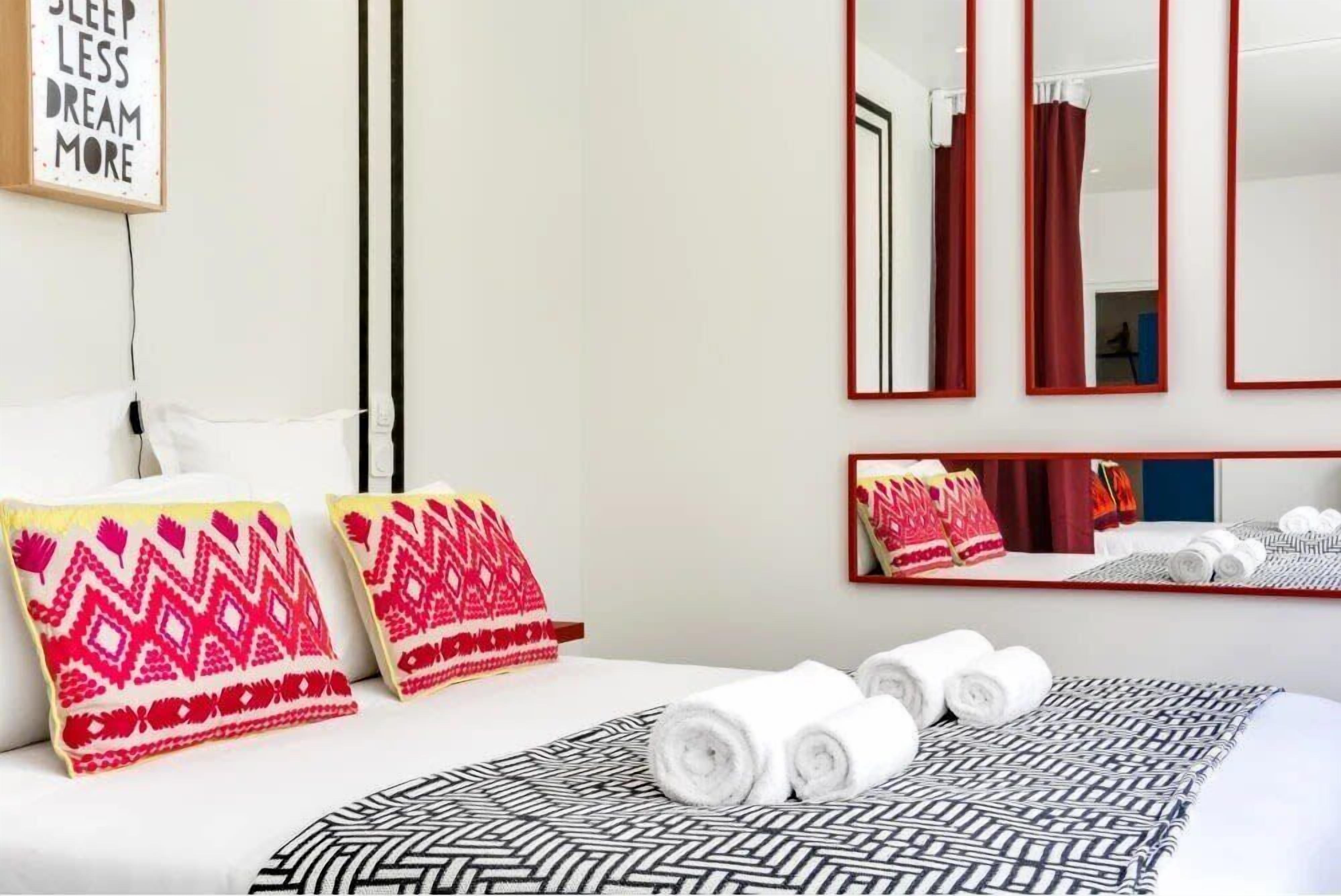 Une chambre d’hôtel avec un lit, des oreillers, une couverture et un miroir.