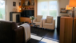 A living room with a sofa, armchairs, a coffee table, a TV, and a fireplace. - Isabelle A1 - Bright family apartment with sunny terrace - in the concession (De Haan)