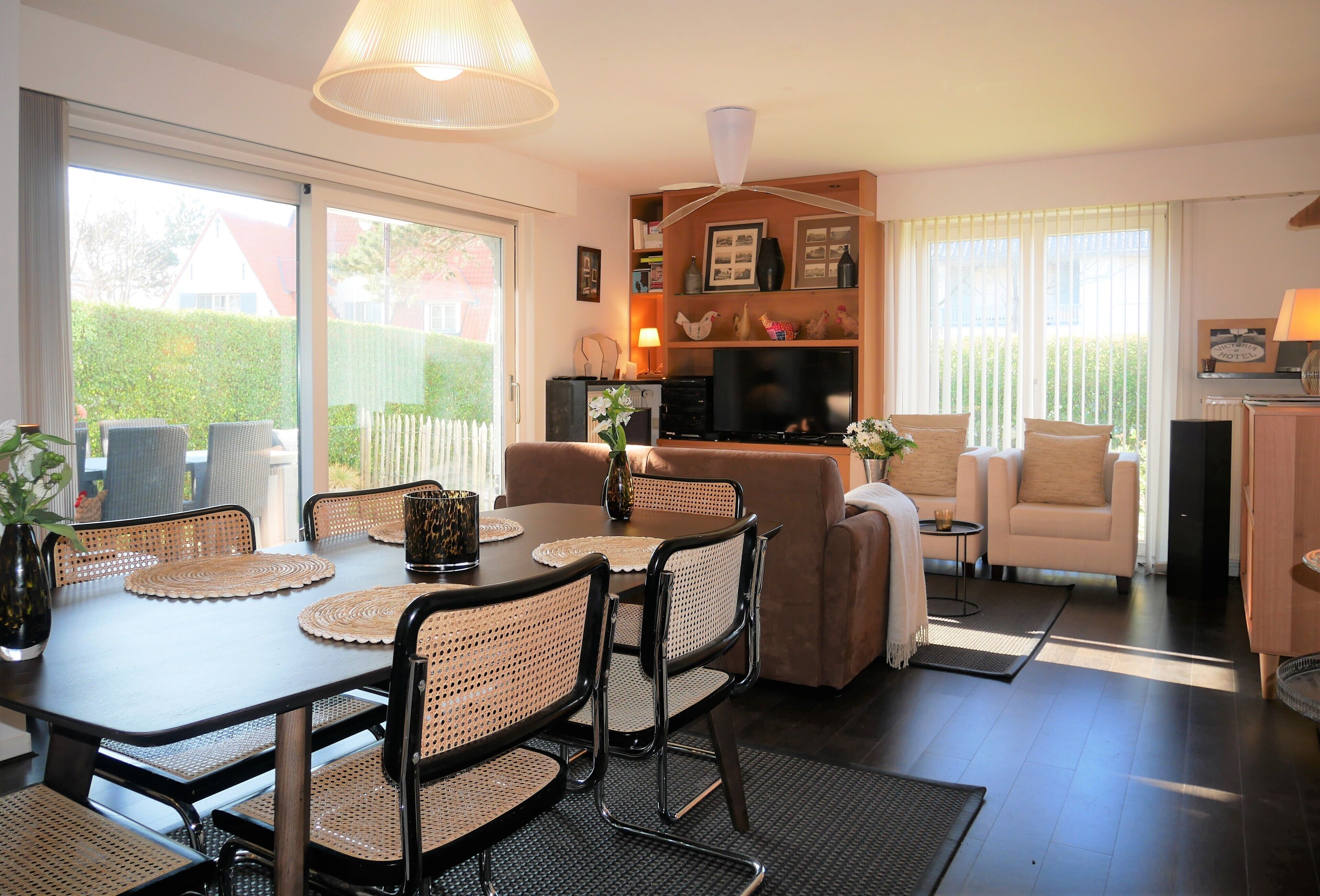 A modern living room with a dining area, a sofa set, a TV, and a fireplace.
