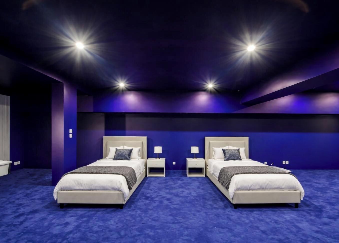 Doble habitación con dos camas, mesitas de noche y alfombra azul.