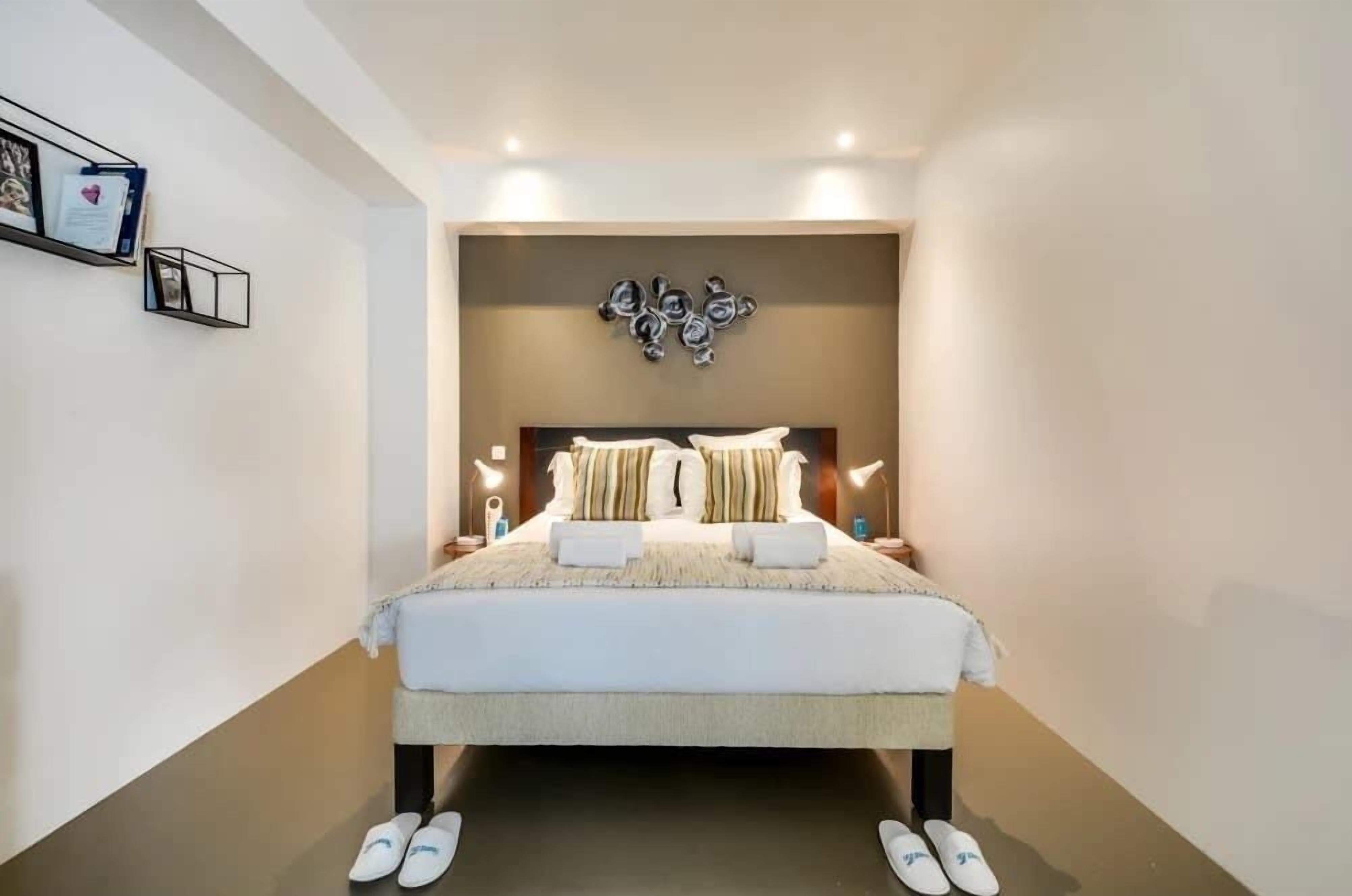 A modern bedroom with a large bed, bedside tables, and wall-mounted artwork.