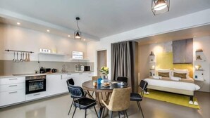 Et moderne hotelværelse med tekøkken, spiseplads og seng.