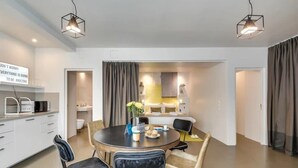 Et moderne spiseområde med et rundt bord, sorte og beige stole og hængende lamper.