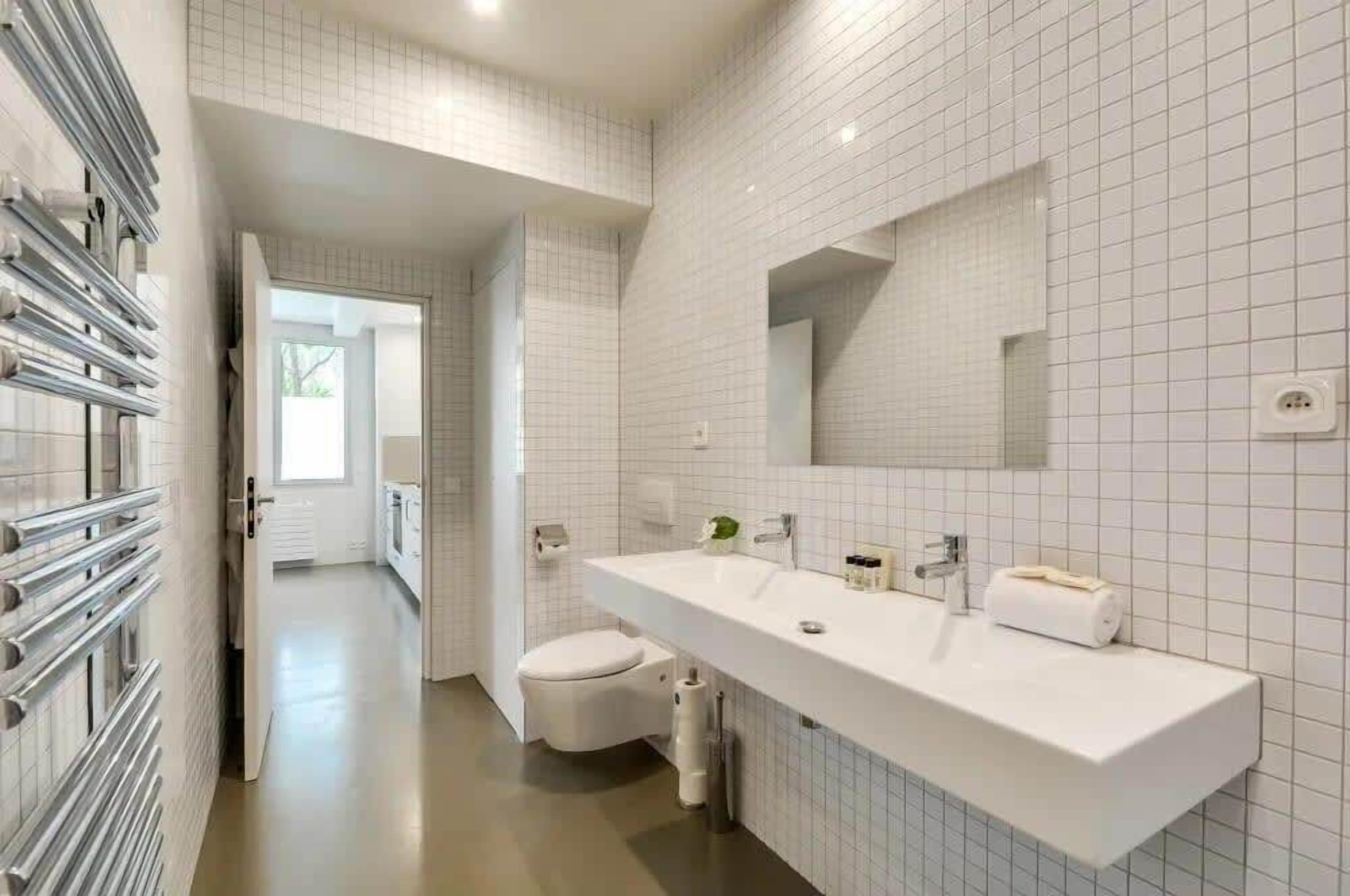 Een moderne badkamer met een witte wastafel, spiegel en toilet.