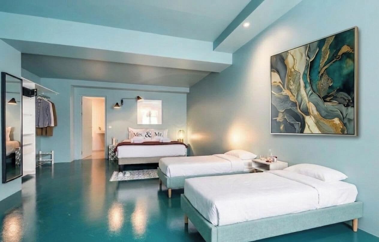 A modern hotel room with two beds, a large abstract painting, and a mirror.
