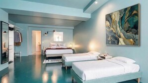 Ein modernes Hotelzimmer mit zwei Betten, einem großen abstrakten Gemälde und einem Spiegel.