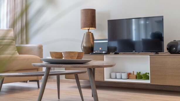 A modern living room with a sofa, a coffee table, a TV, and a lamp.