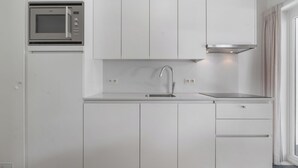 A modern kitchen with white cabinetry, a stainless steel sink, and an integrated microwave.