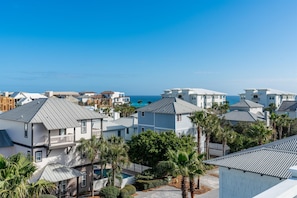 Una zona residencial costera con varias casas, algunas con balcones, y una vista despejada del océano.