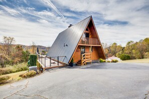 A modern A-frame cabin with a metal roof, wooden exterior, and a small porch.