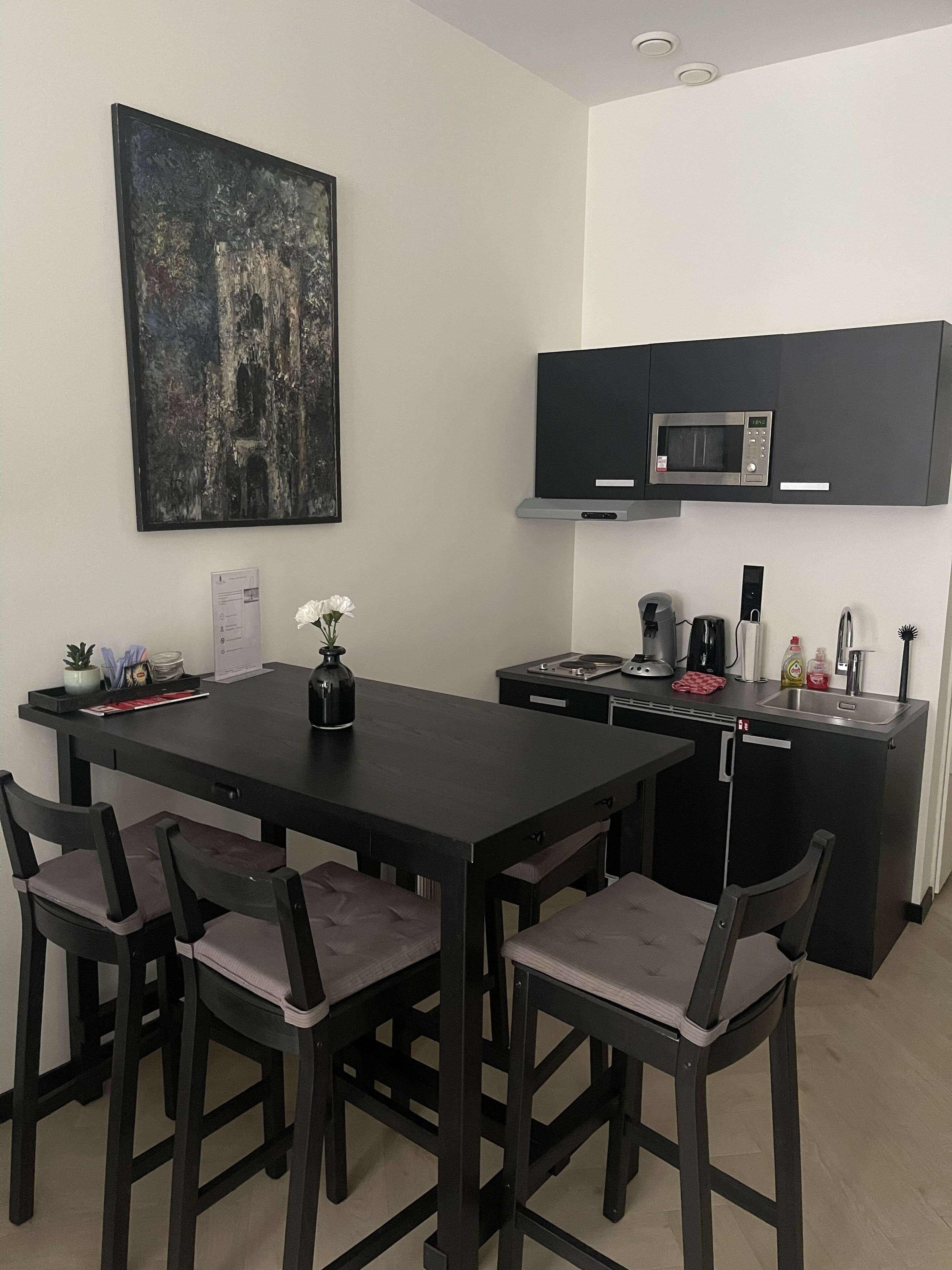 Una cocina moderna con una mesa de comedor, sillas, microondas y cafetera.