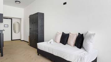 Un dormitorio con cama, armario, espejo y puerta.