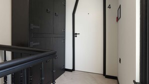 A hallway with a black metal railing, a white door with a black frame, and a number '4' on the wall. - Haarlem Apart Hotel (Haarlem)
