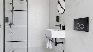 A modern bathroom with a glass-enclosed shower, a white sink with a black faucet, and a towel rack.