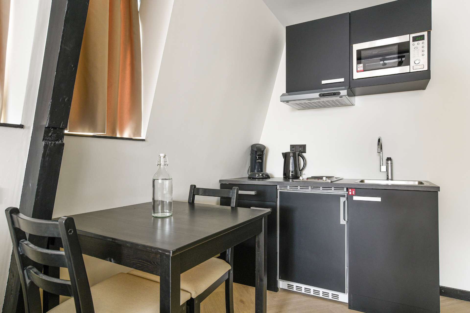 A compact kitchen with a microwave, coffee maker, and refrigerator.