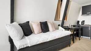 A modern, compact living space with a sofa bed, a small dining area, and a kitchenette. - Haarlem Apart Hotel (Haarlem)