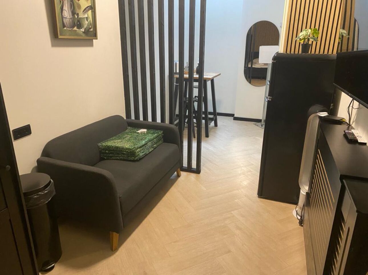 A compact living space with a sofa, a small table, and a kitchenette area.