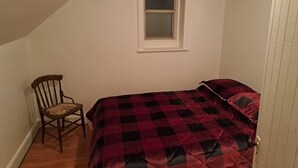 A bedroom with a bed, a chair, a window, and a door. - Historical Square Timber Home right at the heart of Snow Country (Eganville)