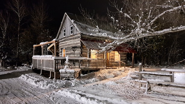 A log cabin with a porch and a snow-covered yard. - Historical Square Timber Home right at the heart of Snow Country (Eganville)