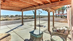 A covered patio with wicker furniture and a ceiling fan, overlooking a desert landscape. - Eloy Desert Oasis w/ Courtyard & Pool Access! (Eloy)