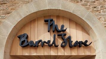 A wooden sign with the text "The Barrel Store" under an arched stone structure.