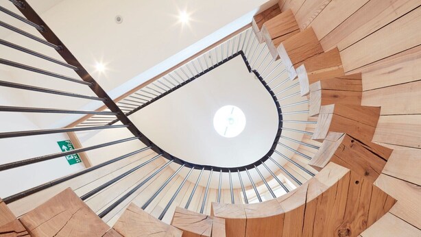A spiral staircase with wooden steps and metal railings, leading to a ceiling with a skylight. - The Barrel Store is a unique hostel in the heart of the Cotswolds. (CIRENCESTER)