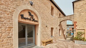 A stone building with a wooden archway entrance labeled "The Barnstone." - The Barrel Store is a unique hostel in the heart of the Cotswolds. (CIRENCESTER)
